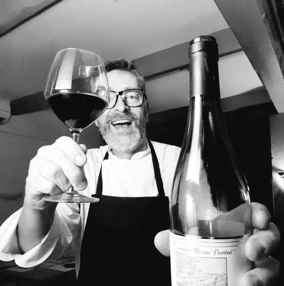 Jean-Robert tenant un verre de vin au restaurant Au Vin sur Vin